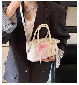 Macro detail of cream Boston bag with cat paw embossing and pink bow pearl charm