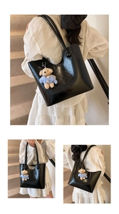 Detail of glossy black tote bag with cute blue sweater bear charm and ball handle decor