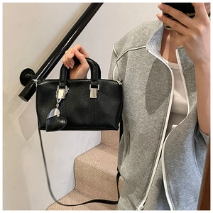 Detail of black lychee grain boston bag with heart charm and silver hardware shown in use