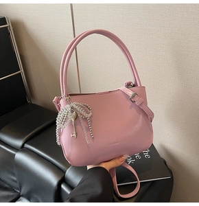 Detail of pink PU leather bucket bag featuring letter embossing and beaded bow charm