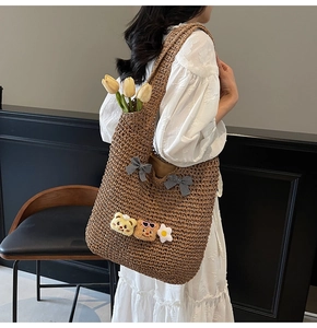 Detail der geflochtenen Strohtasche mit karierten Schleifen und Teddy-Anhängern