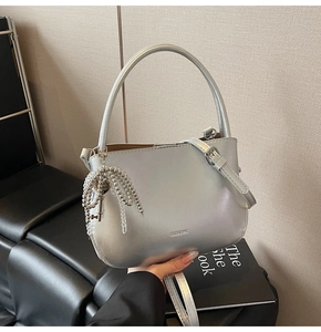 Detail of silver metallic bucket bag with clearzk logo and pearl key pendant charm