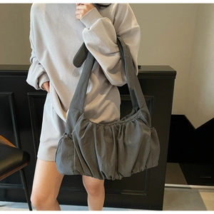 Detalle de bolso nube plisado gris oscuro con correa ancha de hombro y estilo moderno