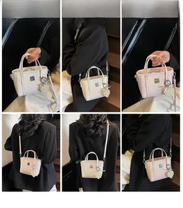 Dettaglio della mini borsa a secchiello con ciondolo a cuore di perle e logo in metallo