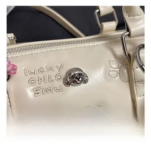 Detail of silver poodle hardware and lucky embroidery on the beige boston bag