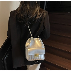 Borsa a secchiello metallizzata argento con chiusura dorata su modella con catena