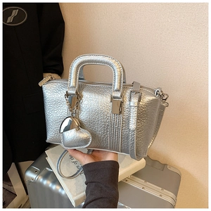 Detail of silver metallic PU leather handbag with heart charm and detachable shoulder strap