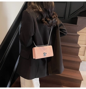 Fashionable pink fish scale chain bag shown on model in a modern urban staircase setting