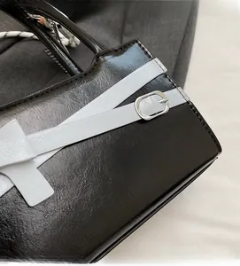 Dettaglio della borsa in pelle nera con trama stropicciata e fibbia in metallo