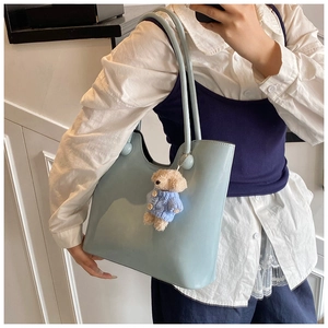 Close-up of light blue PU leather tote bag featuring a cute teddy bear plush charm