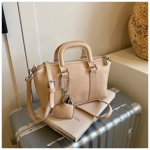 Close-up of litchi pattern PU leather handbag with heart pendant and silver hardware