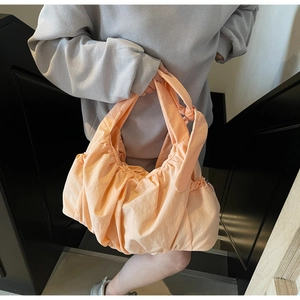 Detalle del bolso nube naranja plisado en nailon con nudo en el asa para un estilo casual