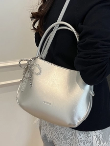 Silver metallic crescent bucket bag with beaded bow charm and crossbody strap