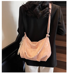 Rear view of a light pink tote bag with braided decoration worn by a model in a black suit