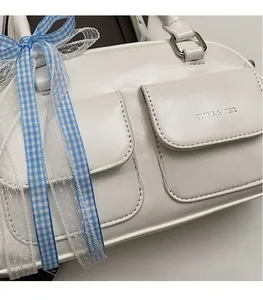 Close-up of white leather Boston bag with dual pockets and decorative blue lace ribbons