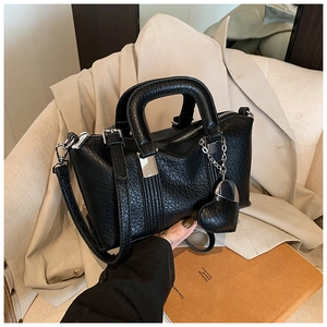 Detail of black pleated PU leather Boston bag with silver hardware and heart charm