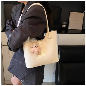 Detail of cream leather shoulder bucket bag with brand logo and cute bear charm