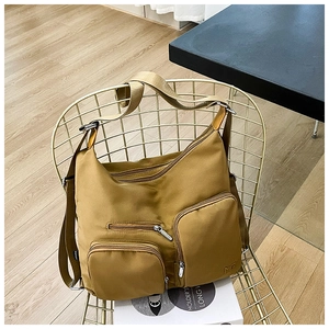 Detailansicht der khakifarbenen Nylontasche mit funktionalen Reißverschlusstaschen und Gurt