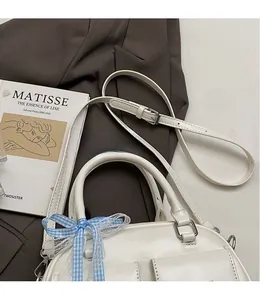 Close-up of a white leather Boston bag featuring a stylish blue checkered ribbon detail
