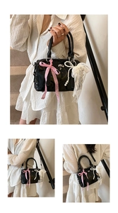 Detailed macro view of black patent leather boston bag with embossed patterns and pearl tassels