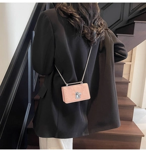 Detail of pink snake-skin texture crossbody bag with silver chain and metal lock