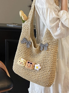 Schicke Strohtasche mit karierten Schleifen und Anhängern für den Sommerstrandurlaub