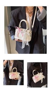 Detail of cream Boston bag featuring heart embossed texture and pink plaid ribbons
