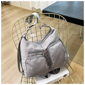 Detailansicht einer grauen Nylon-Umhängetasche mit vielen Taschen auf einem Metallstuhl