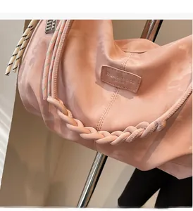 Detail of the braided tote handle with colorful striped accents on a pink nylon bag