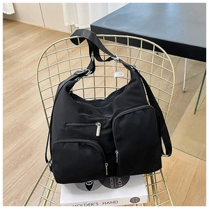 Detail einer schwarzen Nylon-Schultertasche mit Reißverschlüssen und Trageriemen