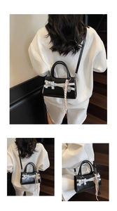 Dettaglio mini borsa nera con fiocco bianco e ciondolo a forma di racchetta da tennis