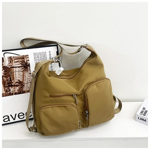 Detail einer ingwergelben Nylon-Schultertasche mit mehreren Taschen und Metall-MG-Logo