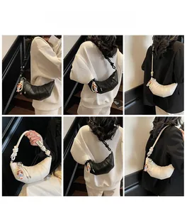 Détail du sac croissant avec bandoulière à nœuds et pendentif en deux couleurs