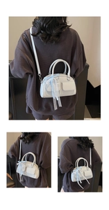 Detail of white Boston bag with light blue plaid bow and embossed front pockets