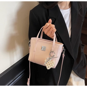 Dettaglio borsa a secchiello in pelle verniciata rosa con logo ZSKE e ciondolo a cuore