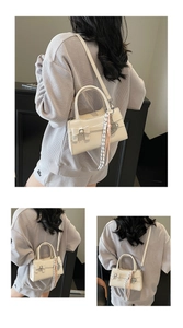Vista posteriore della modella con borsa color crema con fiocco e ciondoli intrecciati
