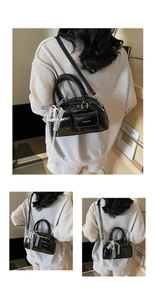 Detail of glossy black faux leather boston bag with white lace bow and dual pockets