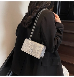 Detail view of silver fish scale textured chain bag worn with a black blazer