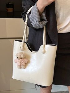 Creamy white leather hobo bucket bag with a cute bear pendant worn by a model