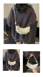 Détail du sac croissant crème minimaliste avec cuir texturé et breloque perle