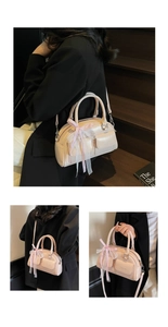 Close-up of pink Boston bag with textured leather and decorative plaid ribbon charm