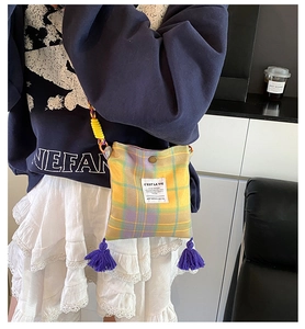 Detail view of plaid crossbody bag featuring purple tassels and C'EST LA VIE label