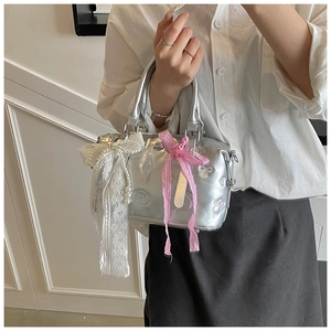 Detailed close-up of silver pillow bag with 3D charms and white lace bow accessories