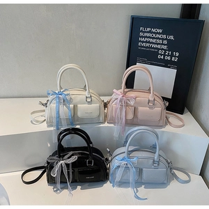 Detail view of four Boston bags in cream, pink, black, and blue on a display stand