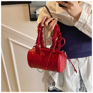 Détail du sac Boston rouge avec surpiqûres en cœur et bandoulière chaîne