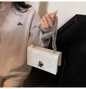 Detailed view of white fish-scale texture on square crossbody bag with silver chain strap
