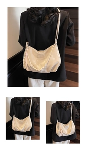 Creamy white glossy hobo bag with woven handle and charm detail shown on model