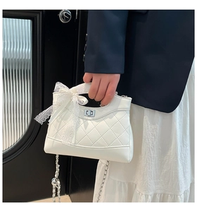 Close-up of quilted white bucket bag with lace bow handle and silver twist lock