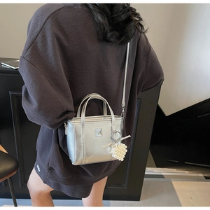 Dettaglio della borsa a secchiello argento con ciondolo di perle su una modella