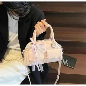 Detailed view of pink Boston bag with decorative bow and front pockets on staircase